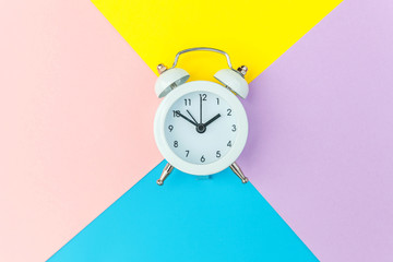Ringing twin bell classic alarm clock isolated on blue yellow pink pastel colorful geometric...