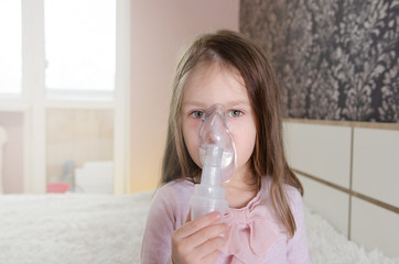 Cute little baby in the mask of an inhaler. Procedure of inhalation at home. Baby taking...