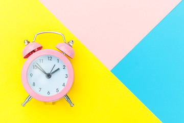 Ringing twin bell classic alarm clock isolated on blue yellow pink pastel colorful geometric background. Rest hours time of life good morning night wake up awake concept. Flat lay top view copy space.