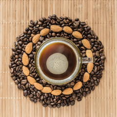 cup of coffee surrounded by coffee beans and almonds