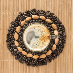 cup of coffee surrounded by coffee beans and almonds