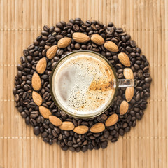 cup of coffee surrounded by coffee beans and almonds