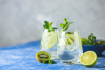 Two detox water, mojito or martini tonic cocktail with kiwi, lime, ice, mint. Summer fresh lime soda cocktail, selective focus. A new kind of mojito with kiwi, lime and mint and of course ice