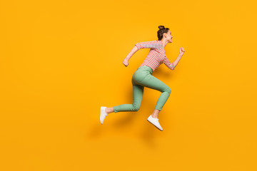 Fototapeta na wymiar Full size profile photo of pretty crazy lady jumping high rushing low prices sales addicted shopper wear red white pullover shirt green pants footwear isolated bright yellow background