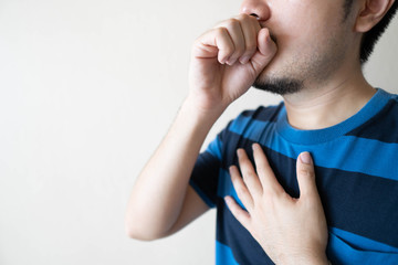 Young ill man have a cough and sore throat over white background. Causes of cough include...