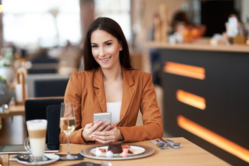 Businesswoman with smartphone at lunch in cafe