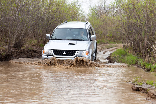 NIKOLAEVKA, RUSSIA - MAY 11, 2015: Mitsubishi Pajero Sport is moving by a big dirty puddle