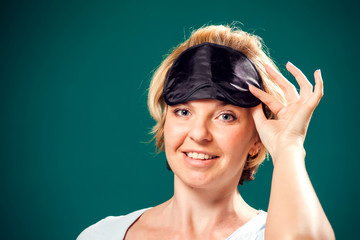 A portrait of smiling woman with sleep mask on head.