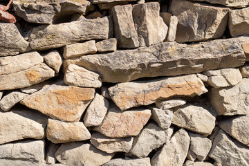 Stone fence wall, stone house. Hard slate slab rock texture, natural narrow brick, beige, yellow, gray