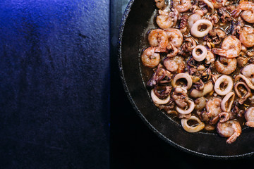 Frying pan with a mix of seafood, octopus, squid rings, shrimp. Seafood in soy sauce. Cooking in a pan.