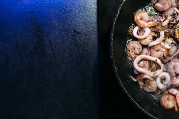 Frying pan with a mix of seafood, octopus, squid rings, shrimp. Seafood in soy sauce. Cooking in a pan.