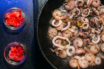 Frying pan with a mix of seafood, octopus, squid rings, shrimp. Seafood in soy sauce. Cooking in a pan.