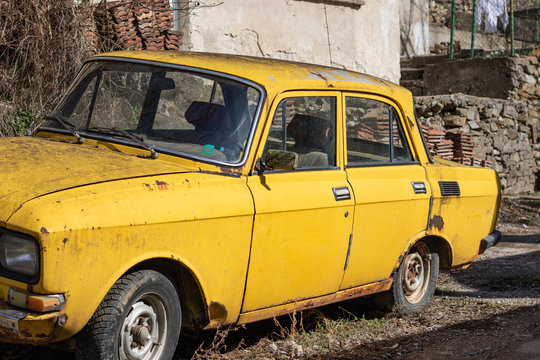 Gabrovo, Bulgaria - March 02. 2020 Old Russian Soviet car - Moskvich - Muscovite in a beautiful yellow color parked in front of an old house in repair. Retro Car from the USSR