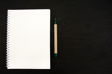 white notebook and pen on a black table. Space for text.