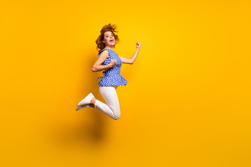 Fototapeta na wymiar Full body profile photo of beautiful crazy lady jump high up fists celebrate champion sportive game wear dotted blue shirt white pants sneakers isolated yellow color background