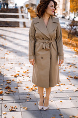 a young woman walks through the autumn city, a happy body female with curly hair in a raincoat.
