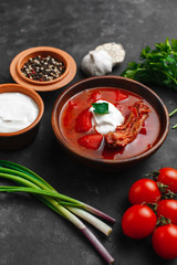 Ukrainian borsch. Beetroot soup. Ukrainian cuisine.In a wooden plate. On dark background. The view from the top. Free space for your text. A bowl of red beet soup with sour cream.