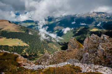 Fototapeta premium Bright colored landscape on wooded meadows and mountains covered with clouds. Sunny day in Seceda in South Tyrol, Dolomites. Mountain camping, travel and hiking