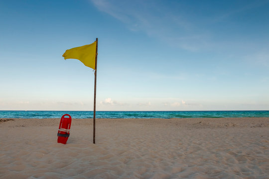 boia de salva vidas ao lado de bandeira amarela na praia