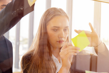 Two business men and women sticking notes on clear glass