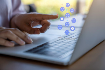 Person using a social media marketing concept on laptop computer with notification icons of like, chat, message and comment above laptop keyboard.