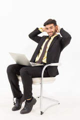 A handsome businessman sitting in a good smile on a chair and having a tablet isolated on white background,