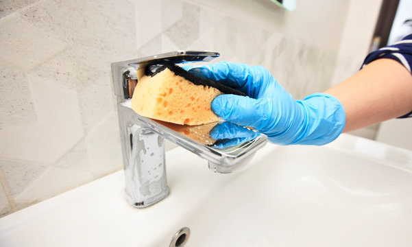 The Young Woman Is Cleaning The Faucet In The Bathroom