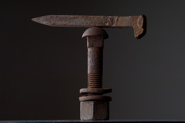 rusty nail balancing on a rusty nut and bolt