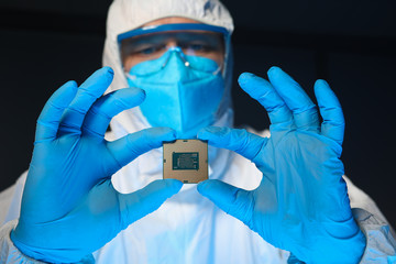 Man in special uniform shows microprocessor chip. Software-controlled device for processing information. Production technology. Development special chip. Scientist is engaged in chip implementation