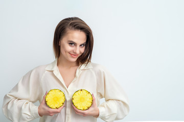 Two halves of pineapple in hands of woman.