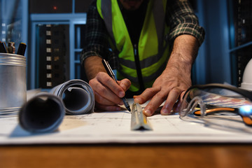 Engineer Designer sketching with Blueprint Architecture on Desk office in-home at night, Working overtime, Maximum working hours, Compulsory overtime.