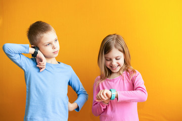 Happy children 6-8 years old with a smart GPS watch talking to parents safely. orange background