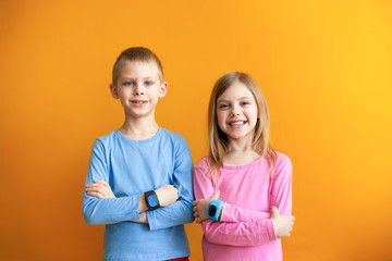 Happy children 6-8 years old with a smart GPS watch talking to parents safely. orange background
