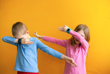 Children 6-8 years old on an orange background with a smart GPS watch make a cool young gesture...
