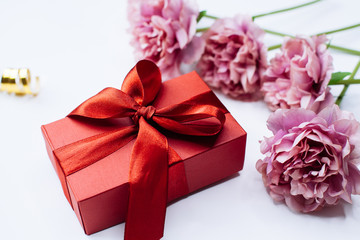 White background with red gift box and peony flowers, top view