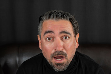Portrait of shocked gasping man on black background.	