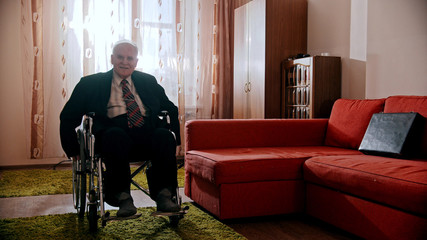 Elderly grandfather - smiling grandfather sitting in a wheelchair in the room