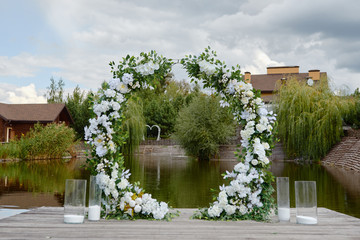 Circle wedding arch decorated with white flowers and greenery outdoors, copy space. Wedding...