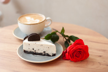 cup of coffee, cake and rose on a wooden table 