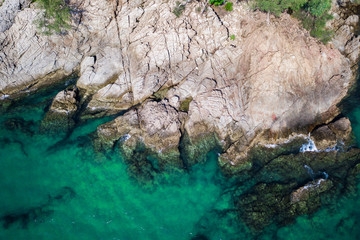 Aerial drone top view of turquoise sea surface with stones and rocks in water