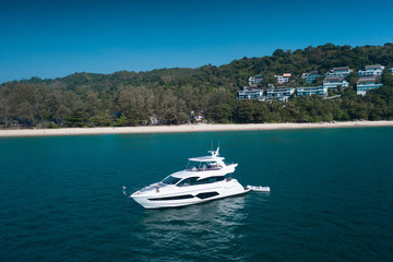 Fototapeta na wymiar Aerial drone view of luxury white yacht in the blue sea with beach in the background. Travel concept
