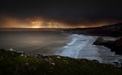 Storm clouds at sunset over Three Cliffs and Oxwich Bay on the Gower peninsula in Swansea, UK