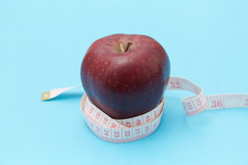 Red apples on the table and a ruler for measuring waistline