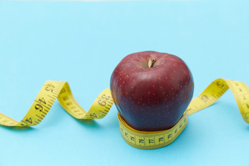 Red apples on the table and a ruler for measuring waistline