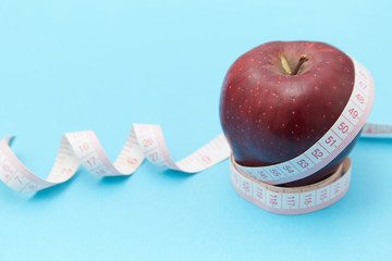 Red apples on the table and a ruler for measuring waistline