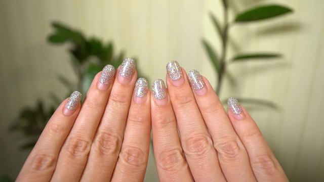 Point of view close-up video shoot of two beautiful female hands with worn several weeks glossy silver manicure. Woman going to make correction of nail design at spa salon. 