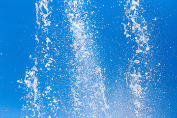 Naklejka na ściany i meble Splashing water from a fountain on a background of blue sky
