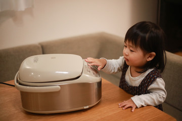 炊飯器に触れる女の子