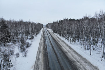 Aerial view of a car on winter road in the forest. Winter landscape countryside. Aerial photography of snowy forest with car on the road. Captured from above with a drone