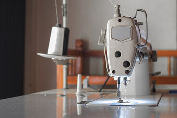 White industrial sewing machine use sew cloth close-up.